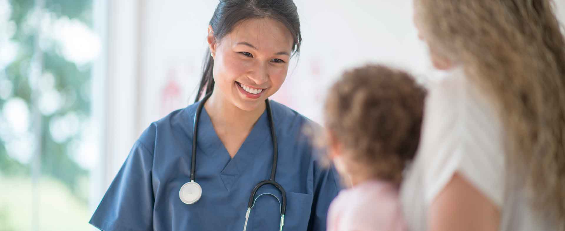 Smiling female physician talking with mother and young child